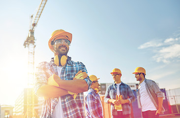 Image showing group of smiling builders in hardhats outdoors