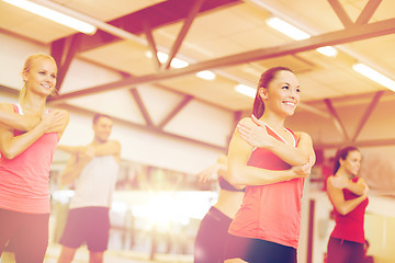 Image showing group of smiling people stretching in the gym