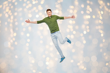 Image showing smiling young man jumping in air