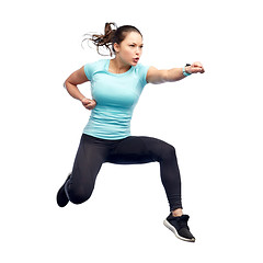 Image showing happy sporty young woman jumping in fighting pose