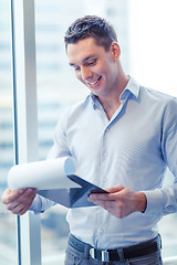 Image showing smiling businessman with clipboard in office