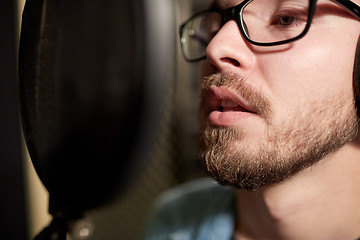 Image showing man with headphones singing at recording studio