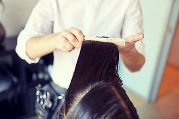 Image showing male stylist hands combing wet hair at salon