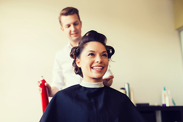 Image showing happy woman with stylist making hairdo at salon