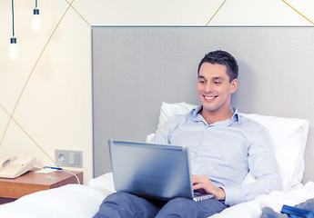 Image showing happy businesswoman with laptop in hotel room