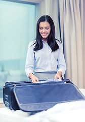 Image showing businesswoman packing things in suitcase