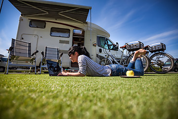 Image showing Woman on the grass, looking at the laptop near the campe.