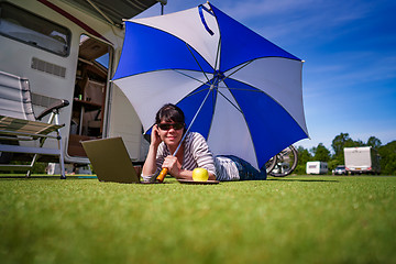 Image showing Woman on the grass, looking at the laptop under umbrella near th