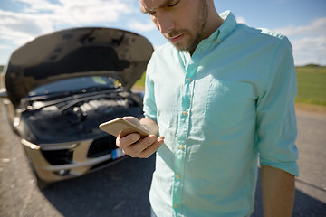 Image showing close up of man with smartphone and broken car