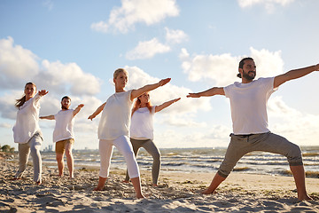 Image showing group of people making yoga exercises on beach