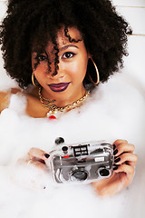 Image showing young afro-american teen girl laying in bath with foam, wearing 