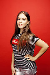 Image showing young pretty emitonal posing teenage girl on bright red background, happy smiling lifestyle people concept