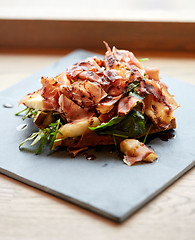 Image showing prosciutto ham salad on stone plate at restaurant