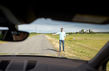 Image showing man hitchhiking and stopping car with thumbs up