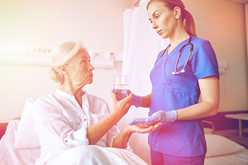 Image showing nurse giving medicine to senior woman at hospital