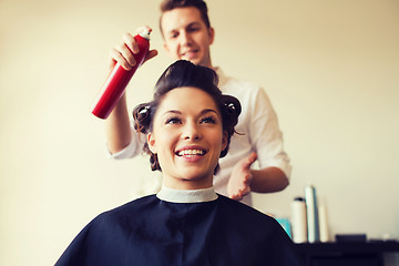 Image showing happy woman with stylist making hairdo at salon