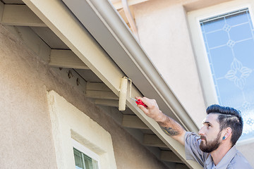 Image showing Professional Painter Using Small Roller to Paint House Fascia