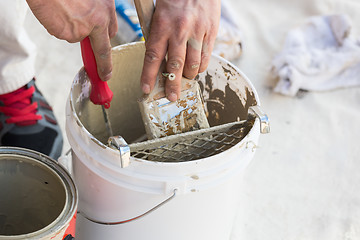 Image showing Professional Painter Loading Paint Onto Brush From Bucket