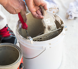 Image showing Professional Painter Loading Paint Onto Brush From Bucket