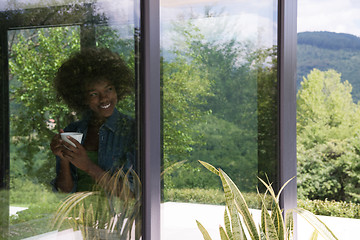 Image showing African American woman drinking coffee looking out the window