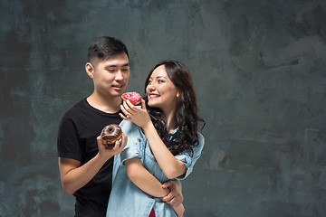Image showing Young asian couple enjoy eating of sweet colorful donut