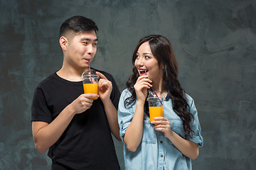 Image showing young pretty Asian couple with  glasses of Orange juice