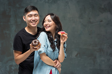 Image showing Young asian couple enjoy eating of sweet colorful donut