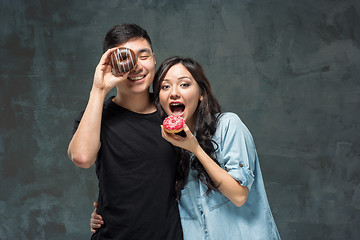 Image showing Young asian couple enjoy eating of sweet colorful donut