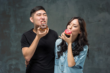 Image showing Young asian couple enjoy eating of sweet colorful donut