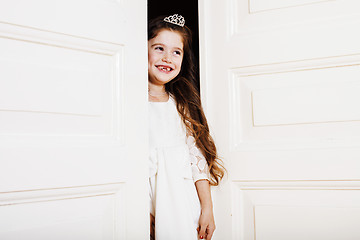 Image showing little cute girl at home, opening door well-dressed in white dre