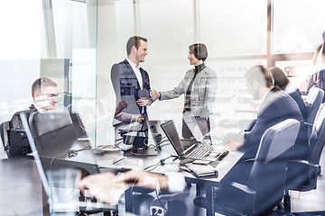 Image showing Business people shaking hands in moder corporate office.