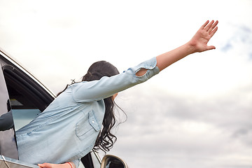 Image showing happy woman waving hand leaning out of car window