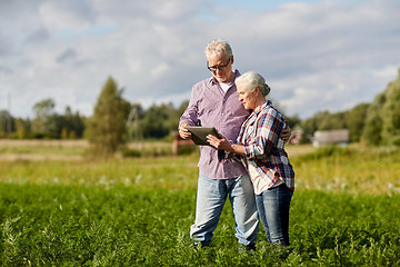 Image showing happy senior couple with tablet pc at summer farm