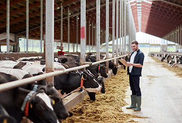 Image showing man with clipboard and cows at dairy farm cowshed