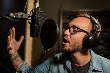 Image showing man with headphones singing at recording studio