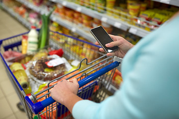 Image showing woman with smartphone buying food at supermarket