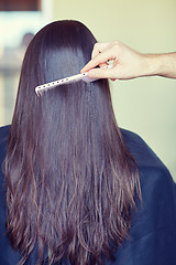 Image showing hand with comb combing woman hair at salon