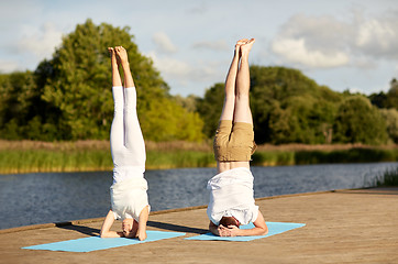 Image showing couple making yoga headstand on mat outdoors