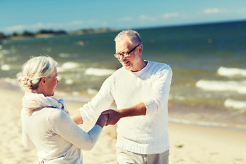 Image showing happy senior couple holding hands on summer beach