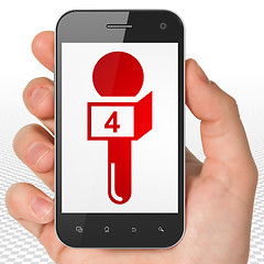 Image showing News concept: Hand Holding Smartphone with Microphone on display