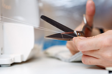 Image showing Woman cuts thread with scissors