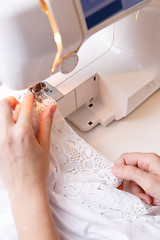 Image showing Girl scribbles fabric on sewing-machine