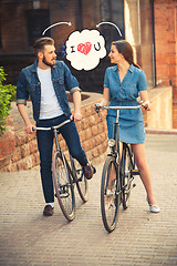 Image showing Young couple sitting on a bicycle opposite city 