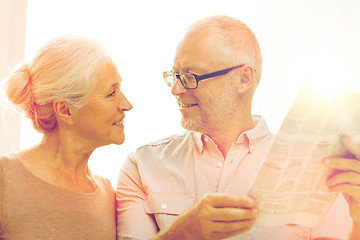 Image showing happy senior couple reading newspaper at home