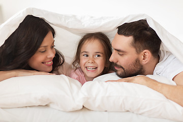 Image showing happy family lying in bed under blanket at home