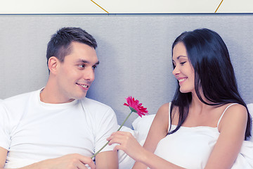 Image showing smiling couple in bed with flower