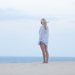 Image showing Woman on sandy beach in white shirt at dusk. 