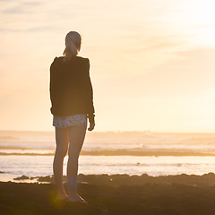Image showing Woman on sandy beach watching sunset.