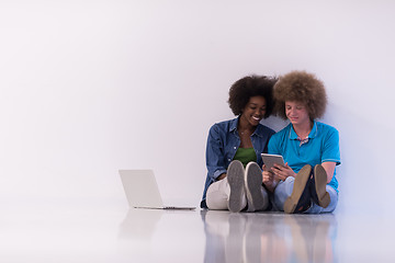 Image showing multiethnic couple sitting on the floor with a laptop and tablet