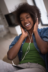 Image showing African american woman at home in chair with tablet and head pho